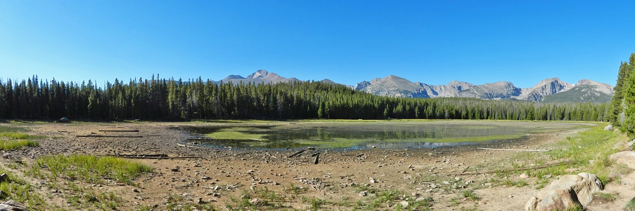 Panoramic view of a serene lakeside landscape with mountains in the background